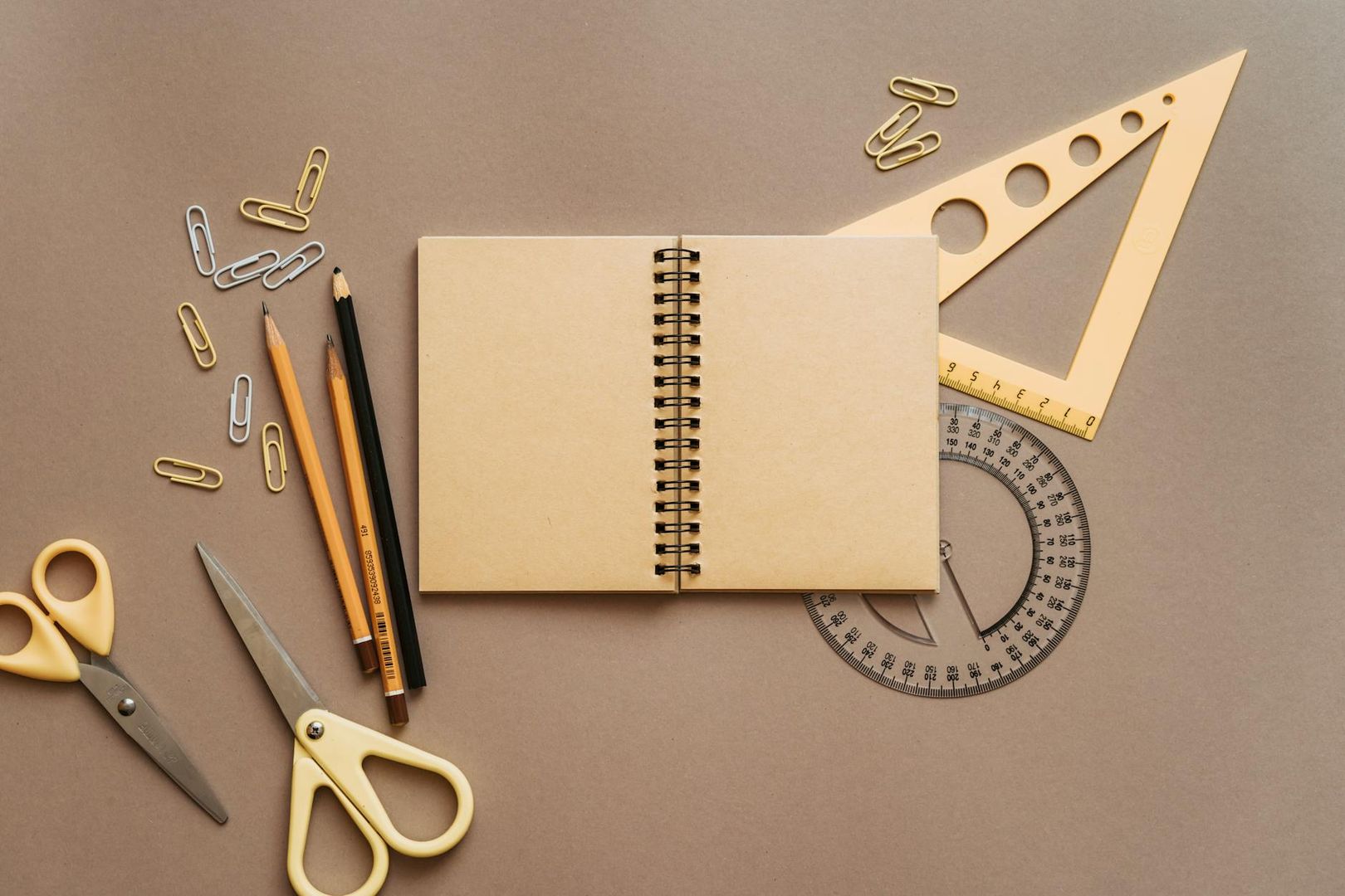 School stationery and an open spiral notebook on a brown desk.
